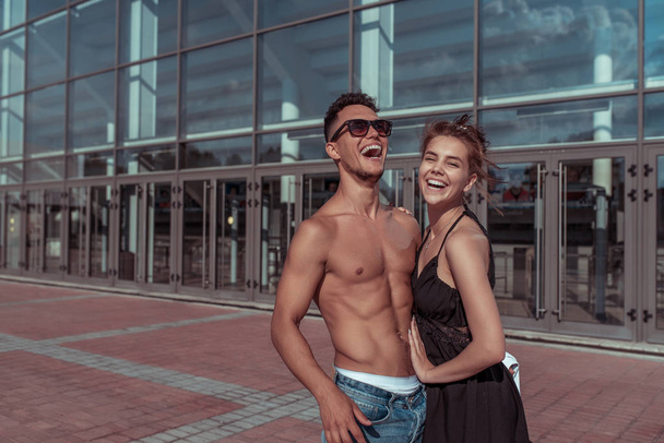 Happy cheerful couple man girl laughing, dancers trained tanned torso, sport dancing, summer city, hip hop, style dancing, youth lifestyle. Street urban fitness. Free space for copy text. - Photo, Image