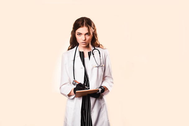 happy beautiful female doctor in medical coat .Writes a medical history in notebook. with a phonendoscope.black medical gloves. going for morning examination of patients in ward of clinic - Foto, immagini