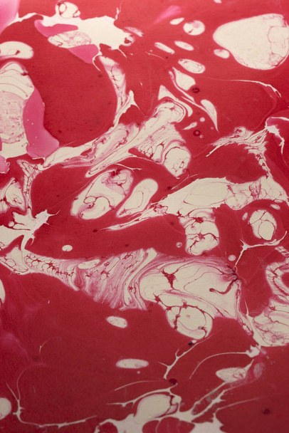 Αυτή είναι μια φωτογραφία ενός κόκκινου και λευκού αφηρημένου μαρμαροποιημένου σχεδίου που δημιουργήθηκε χρησιμοποιώντας βερνίκι νυχιών - Φωτογραφία, εικόνα