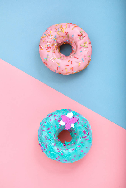 Kaksi donitsia vaaleanpunaisella ja sinisellä pohjalla. Minimalismi luova elintarvikkeiden koostumus. Tasainen lay tyyli
 - Valokuva, kuva