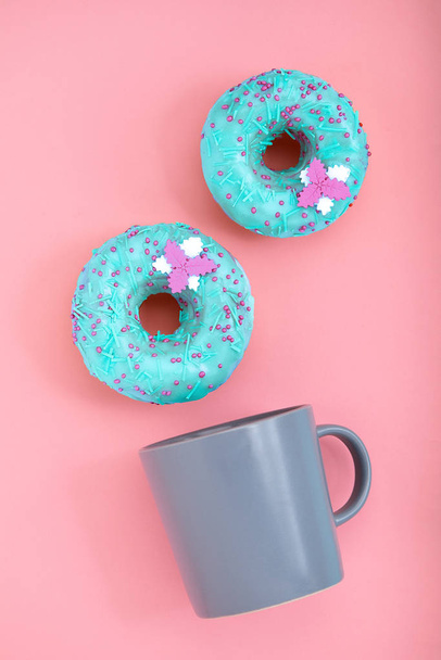 Ciambelle blu con glassa e tazza di caffè su sfondo rosa pastello. Ciambelle dolci
. - Foto, immagini