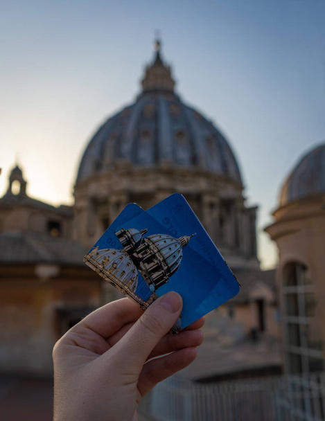 Dívka drží dva lístky do kupole baziliky svatého Petra z Vatikánu před kupolí. Zaměření na lístky, rozmazané pozadí - Fotografie, Obrázek