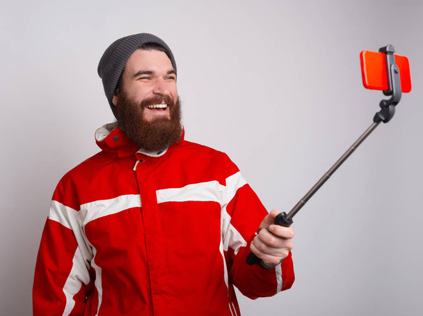 Foto eines glücklichen bärtigen Alpinisten, der ein Selfie mit dem Smartphone macht - Foto, Bild