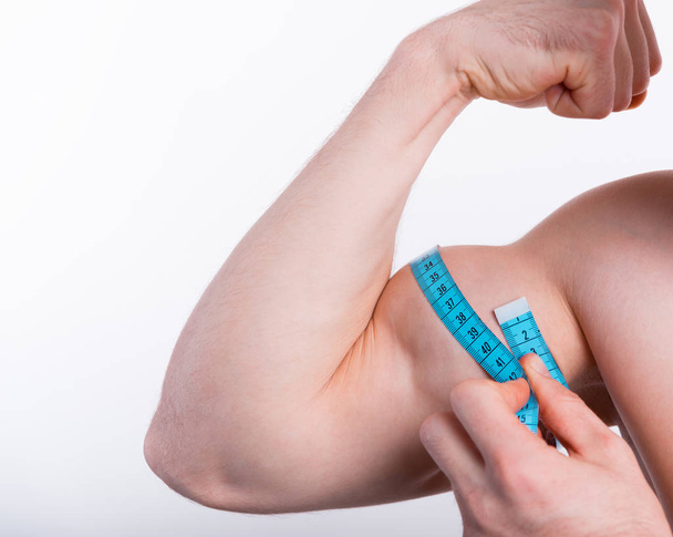 Foto de cerca del hombre de fitness midiendo bíceps con cinta adhesiva
 - Foto, Imagen