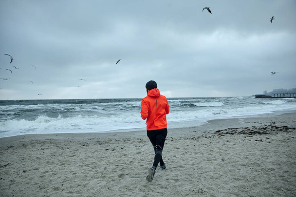 Sıcak spor elbiseli aktif sporcunun çalışma gününden önce deniz kenarında koşup fiziksel egzersiz yaptığı fotoğraf sağlıklı ve sportif bir yaşam sürüyor. - Fotoğraf, Görsel