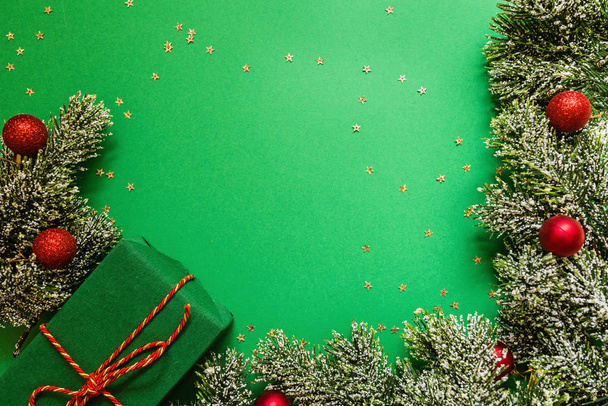 caja de regalo envuelto navidad y ramas de árbol sobre fondo verde con confeti. concepto de año nuevo. Tarjeta de felicitación, celebración de Navidad 2020. Plano, plantilla, vista superior, espacio para copiar
 - Foto, imagen