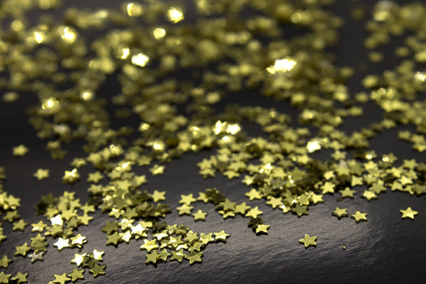 Αυτή είναι μια φωτογραφία από χρυσές πούλιες αστεριών τοποθετημένες σε μαύρο φόντο - Φωτογραφία, εικόνα