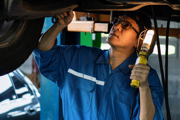 Asyalı erkek araba tamircisinin portresi araba kontrolü yapıyor ve...  - Fotoğraf, Görsel