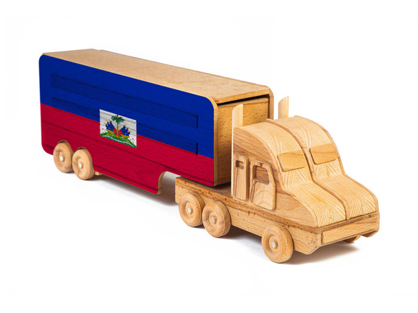 Зблизька дерев'яна іграшкова вантажівка з намальованим національним прапором Гаїті. Концепція експорту-імпорту, транспорту, національного постачання товарів.  - Фото, зображення