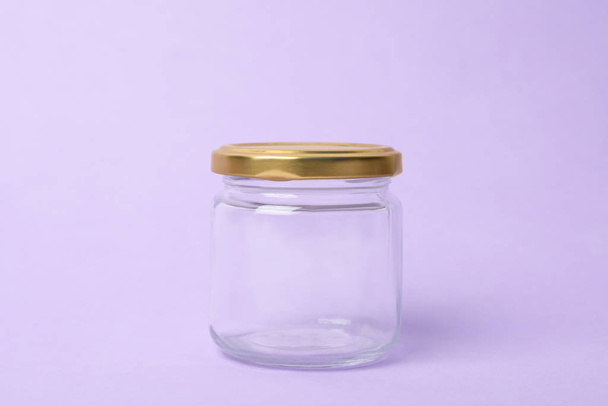 Closed empty glass jar on lilac background - Photo, image