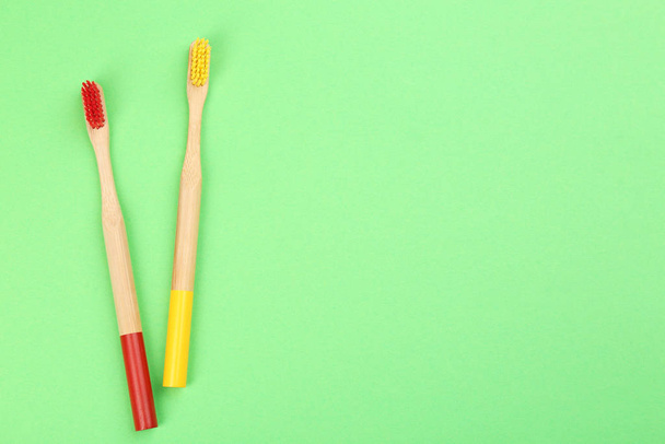 Natural bamboo toothbrushes on green background, flat lay. Space - Φωτογραφία, εικόνα