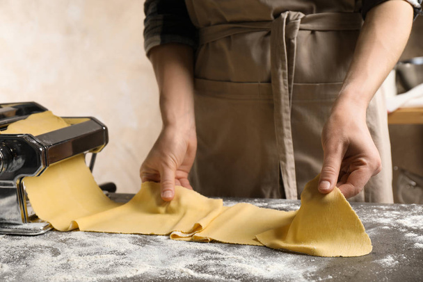 Woman preparing dough with pasta maker machine at grey table, cl - Fotoğraf, Görsel