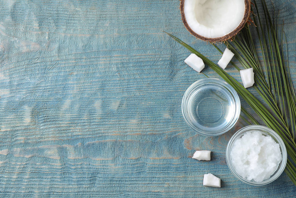 Plochá kompozice s kokosovým olejem na světle modrém dřevěném stole, prostor pro text - Fotografie, Obrázek