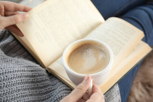 Woman with cup of coffee reading book at home, closeup - Photo, image