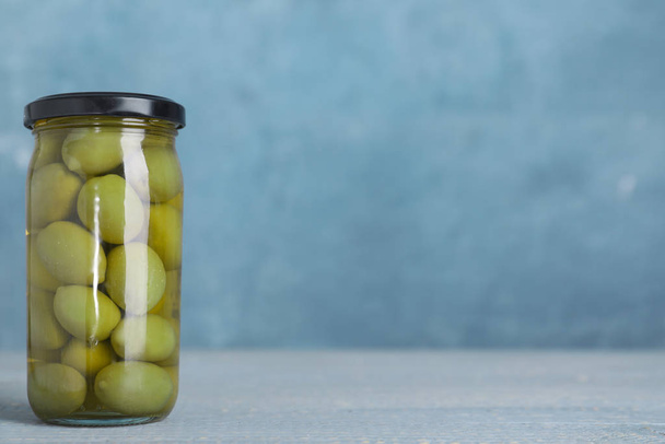 Glass jar with pickled olives on table. Space for text - Fotoğraf, Görsel