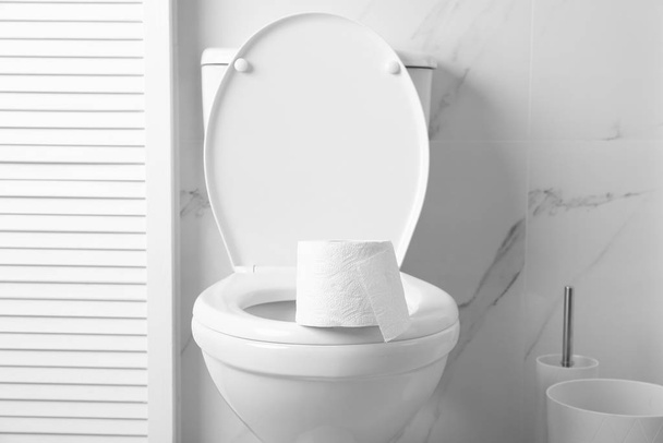 New paper roll on toilet bowl in bathroom - 写真・画像