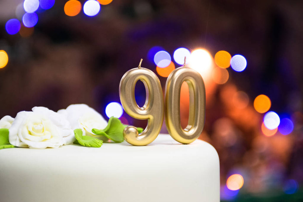Number 90 gold celebration candle on star and glitter background. - Foto, afbeelding