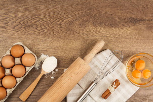 Flat lay composition with raw eggs and other ingredients on wooden background, space for text. Baking pie - Valokuva, kuva