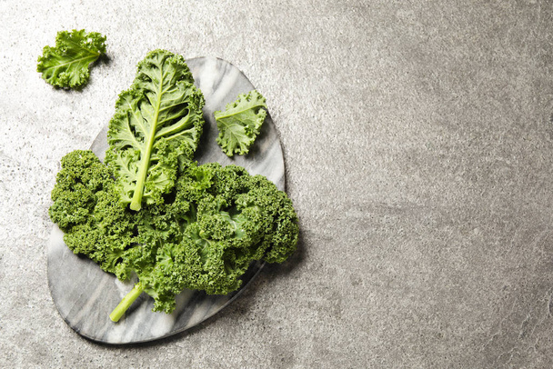Fresh kale leaves on grey table, flat lay. Space for text - Фото, изображение