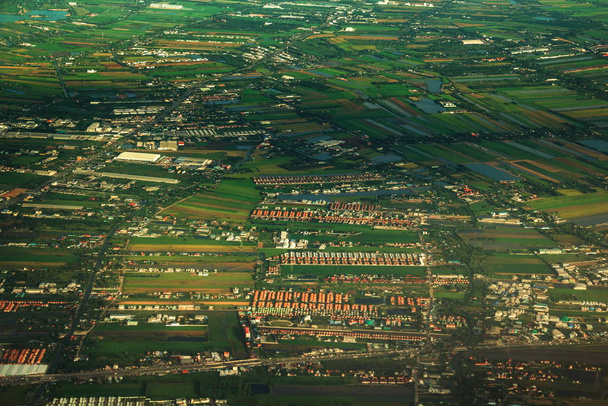 Luchtfoto van de omliggende woonwijk en groene rijstvelden op het platteland, naast de Chao Phraya rivier. - Foto, afbeelding