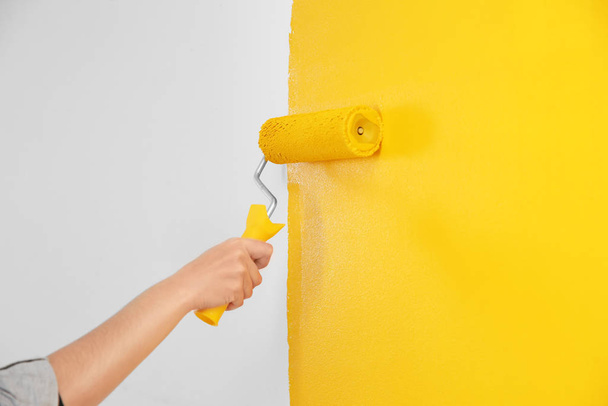 Woman painting white wall with yellow dye, closeup. Interior renovation - Valokuva, kuva