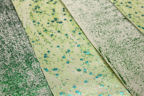Esta es una fotografía de un fondo abstracto creado por la organización de rayas creadas con pintura de brillo verde claro y oscuro y lentejuelas estrella
 - Foto, imagen