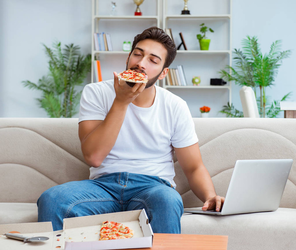 Ο άνθρωπος τρώει πίτσα έχει ένα takeaway στο σπίτι χαλαρωτική ανάπαυση - Φωτογραφία, εικόνα