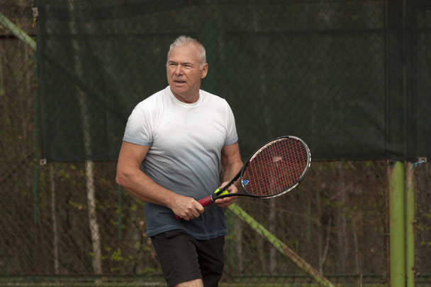 Άντρας που παίζει τένις στο υπαίθριο γήπεδο - Φωτογραφία, εικόνα