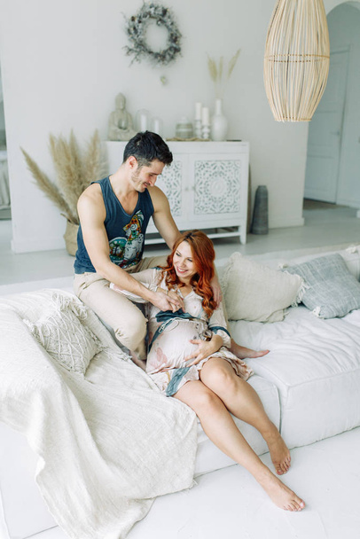 Pregnant woman in arms on the bed. Happy couple expecting a baby.  - Foto, Imagem