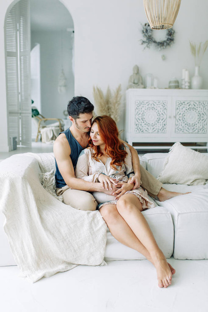 Pregnant woman in arms on the bed. Happy couple expecting a baby.  - Foto, immagini