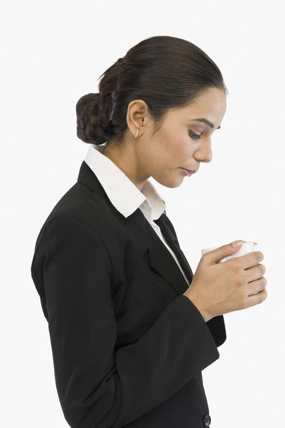 Businesswoman blowing on a cup of tea - 写真・画像