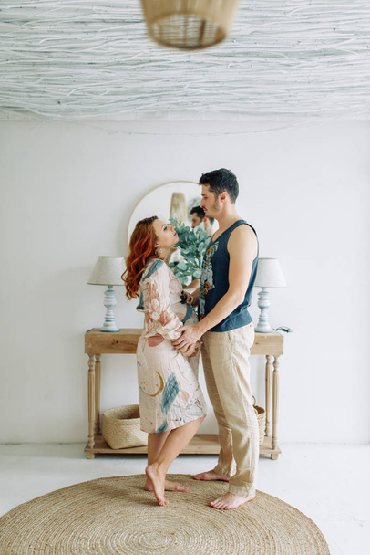 Pregnant woman in arms in white clothes. Happy couple expecting a baby.  - Foto, Imagem