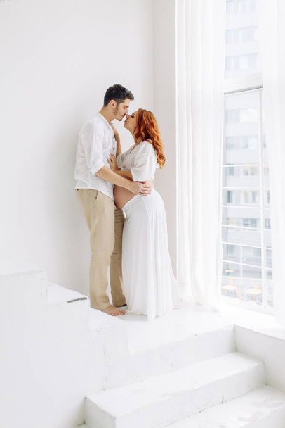 Pregnant woman in arms in white clothes. Happy couple waiting for a tropical baby.  - Foto, imagen