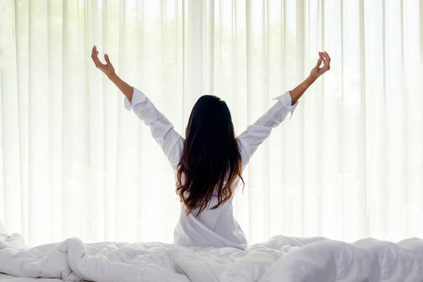 Азіатські жінки прокидається розтягування в ліжку вдома, вранці і сонячний день. Концепція способу життя  - Фото, зображення