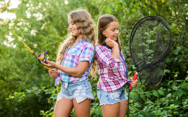 Happy childhood. Adorable girls nature background. Teamwork. Camping activities. Fly fishing. Kids spend time together fishing. Fishing skills. Summer hobby. Happy smiling children with net and rod - Foto, Imagen
