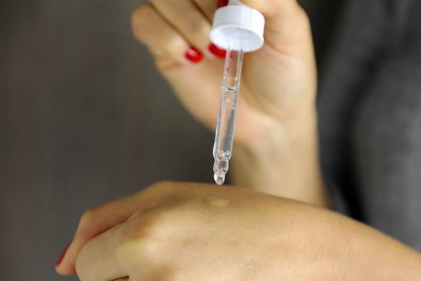Vrouwelijke handen die serum collageen moisturizer laten vallen. Beschermende huid - Foto, afbeelding