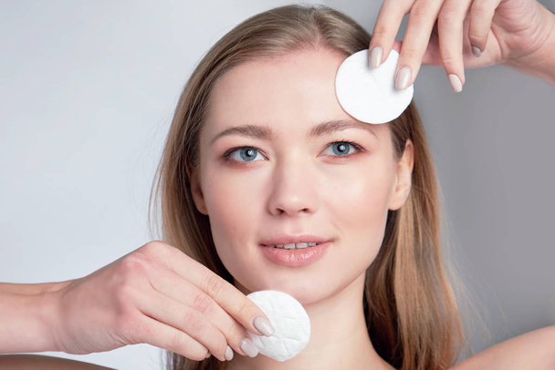 Healthy fresh girl removing makeup from her face with cotton pad. woman with a sponge wihte background cotton pad problem skin - Foto, Imagen