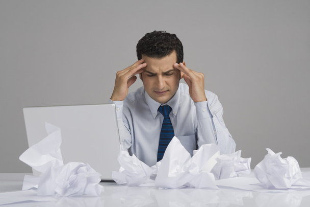 Businessman looking worried with crumpled papers on desk - Фото, зображення