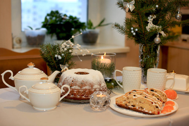 Kerst cupcake met gedroogde vruchten van pruimen, rozijnen, gedroogde kersen en noten op de achtergrond van een theeservies, kerstboomtakken en een aangestoken kaars - Foto, afbeelding