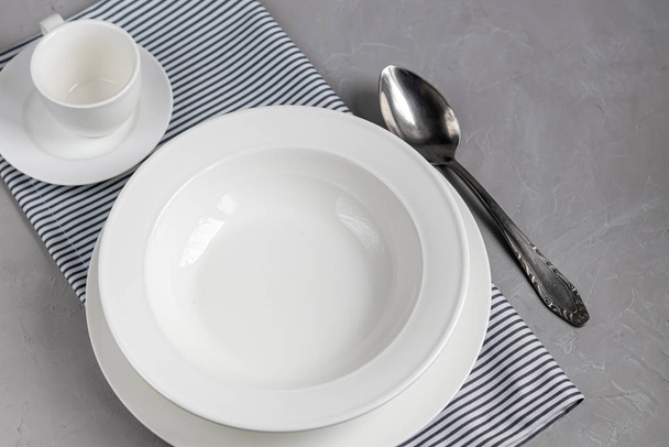 Aménagement des repas. Magnifique service sur une serviette en lin gris. Une assiette pour la soupe ou un plat d'accompagnement. Fond gris clair et plaques blanches
. - Photo, image
