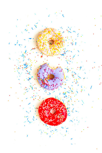 Rosquillas de colores con salpicaduras de colores sobre fondo blanco. Primer plano
 - Foto, imagen