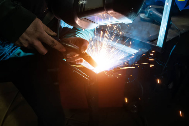 The welder cooks the frame. The welder cooks the metal. The welder cooks metal structures. Welding works. Sparks, molten metal - Foto, Bild