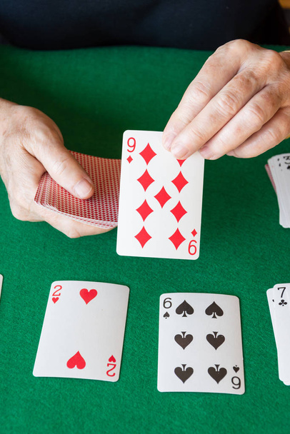 Top nézet póker kártyák zöld szőnyegen női kéz játszik pasziánsz, függőleges - Fotó, kép
