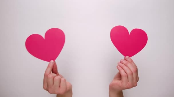 Γυναικεία χέρια που κρατούν κόκκινες χάρτινες καρδιές μέσα από λευκό χάρτινο τοίχο. Ημέρα του Αγίου Βαλεντίνου και όπως blogging blog έννοια τρυφερότητας του κοινωνικού δικτύου. - Πλάνα, βίντεο