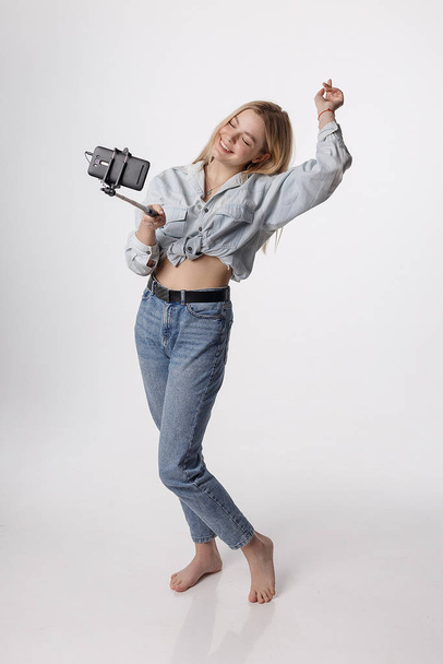 happy young girl making self portrait with smartphone attached to selfie stick - Foto, Imagen
