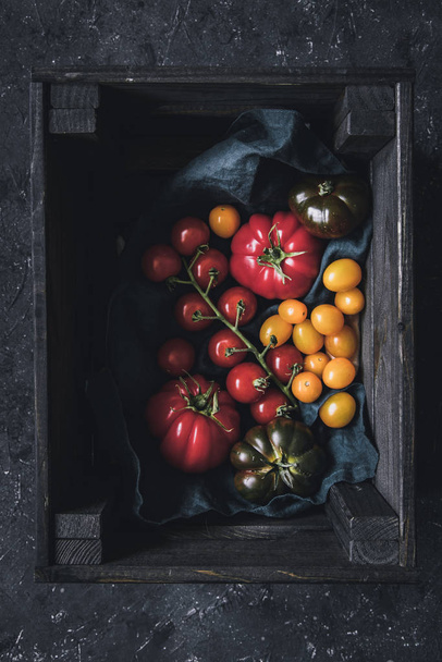 Ripe colorful different tomatoes in wooden box. - Фото, изображение