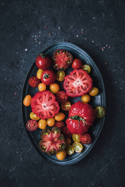 Colourful beautiful tomatoes on plate, view from above - Foto, afbeelding