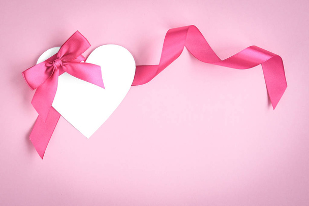 Белые бумажные валентинки сердце с розовыми лентами и лук на розовом фоне с копировальным пространством
. - Фото, изображение