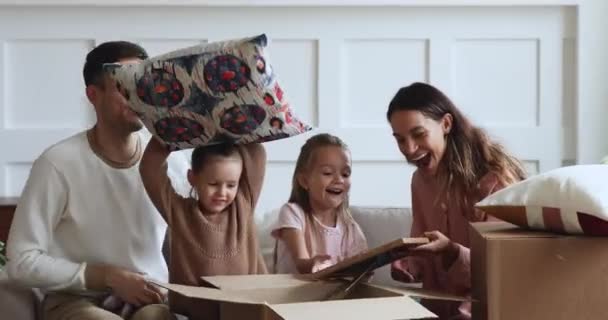 Excited family with kids unpacking boxes together on moving day - Materiał filmowy, wideo