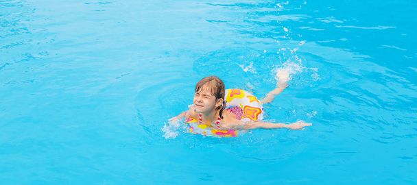 L'enfant nage dans la piscine en été. Concentration sélective. - Photo, image